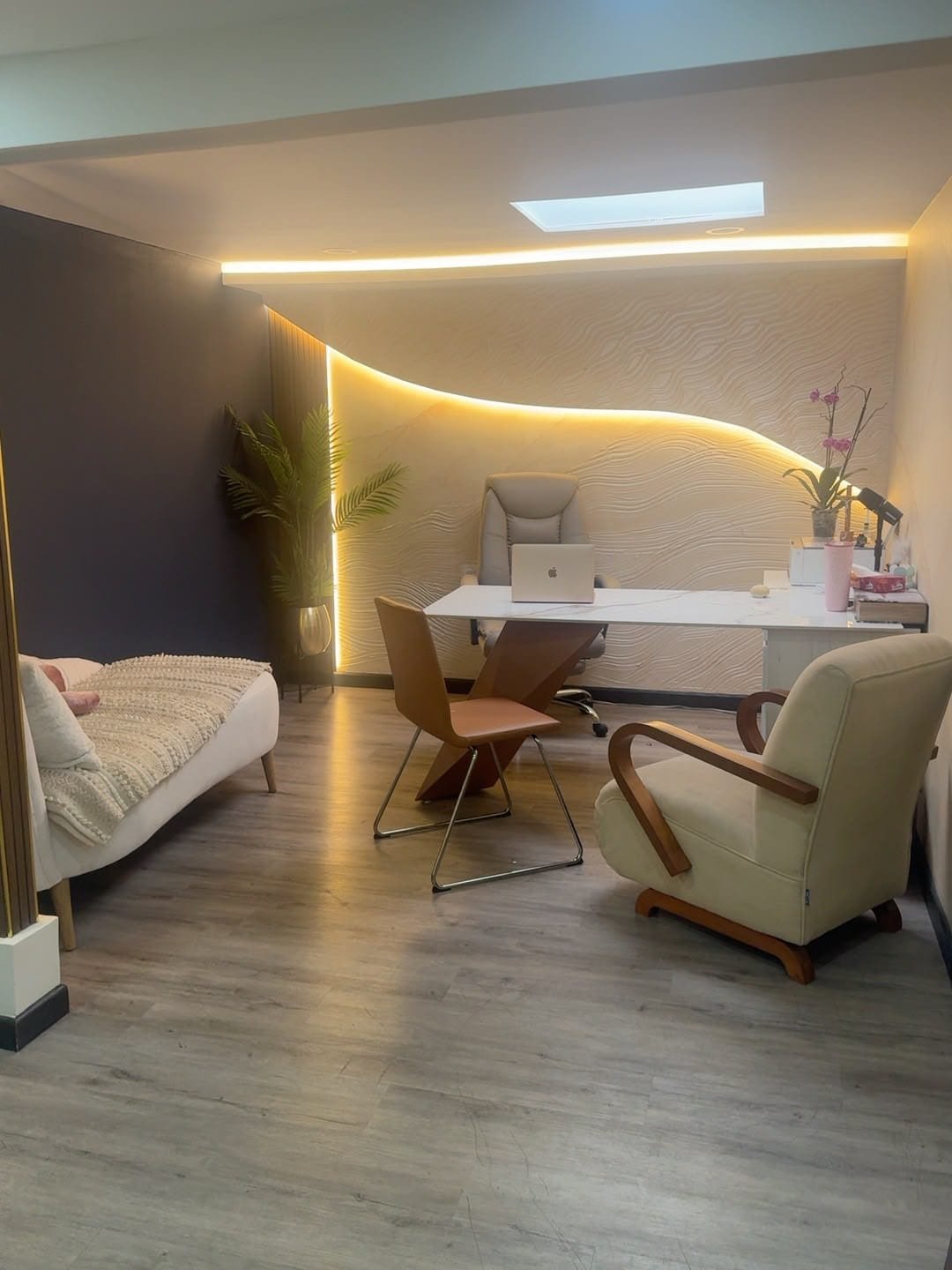 Consultorio de psicología organizado, con escritorio, computador y sillón